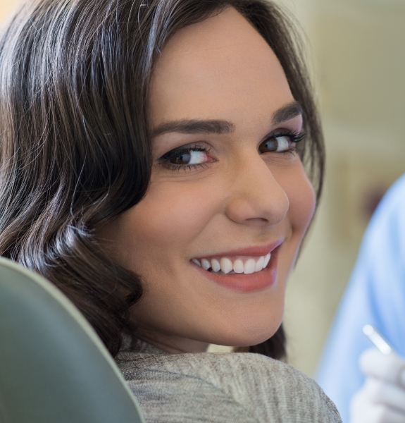Woman in dental chair sharing healthy smile