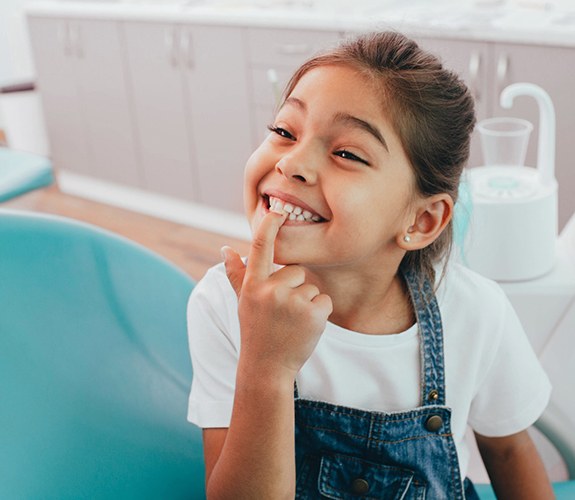 Girl smiling and pointing to teeth after Phase 1 orthodontics in Sycamore , IL